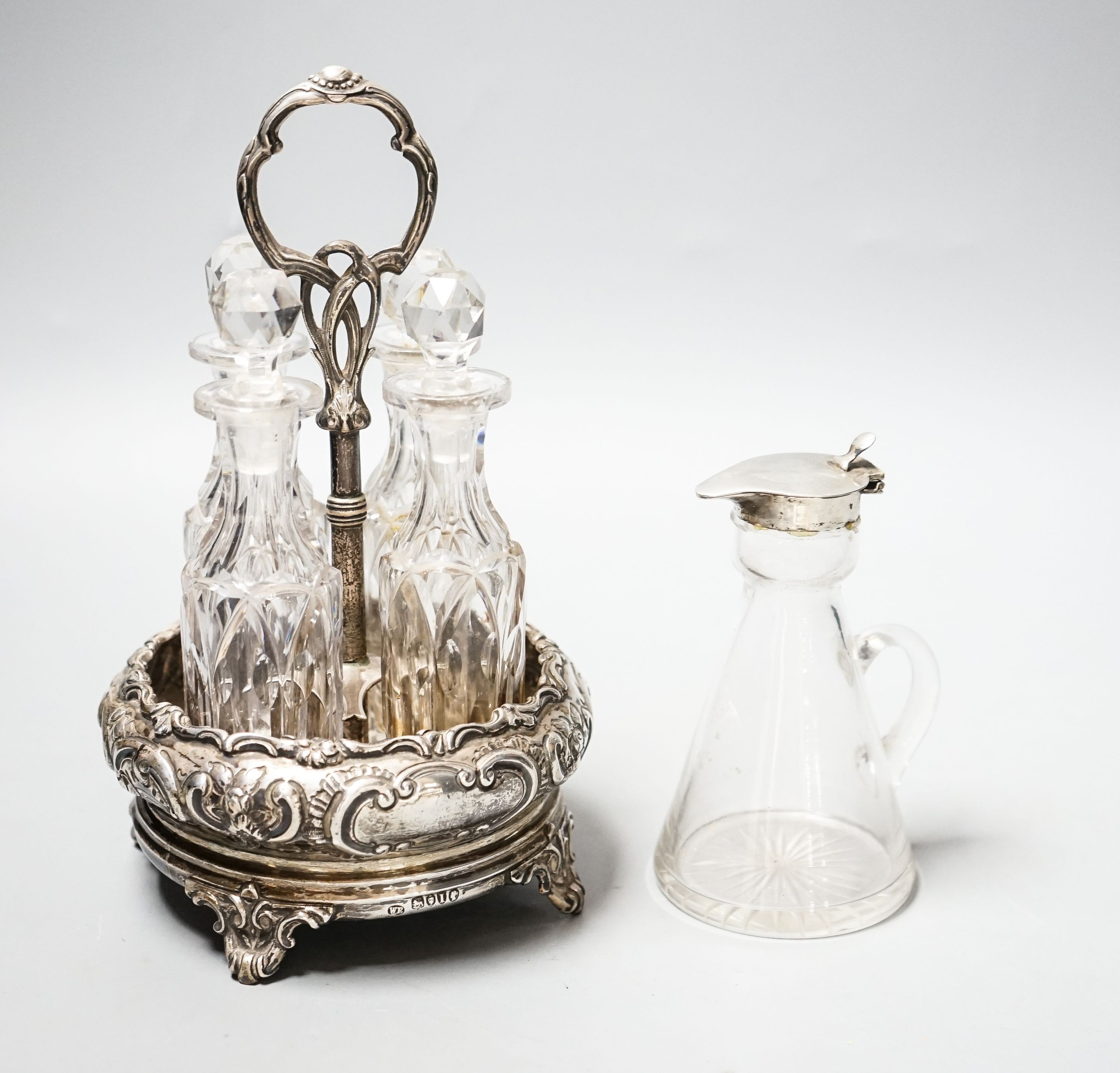A late Victorian silver circular four division cruet stand, William Evans, London, 1884, height 20.5cm, with four glass bottles, together with a George V silver mounted glass whisky tot jug, Birmingham, 1923.